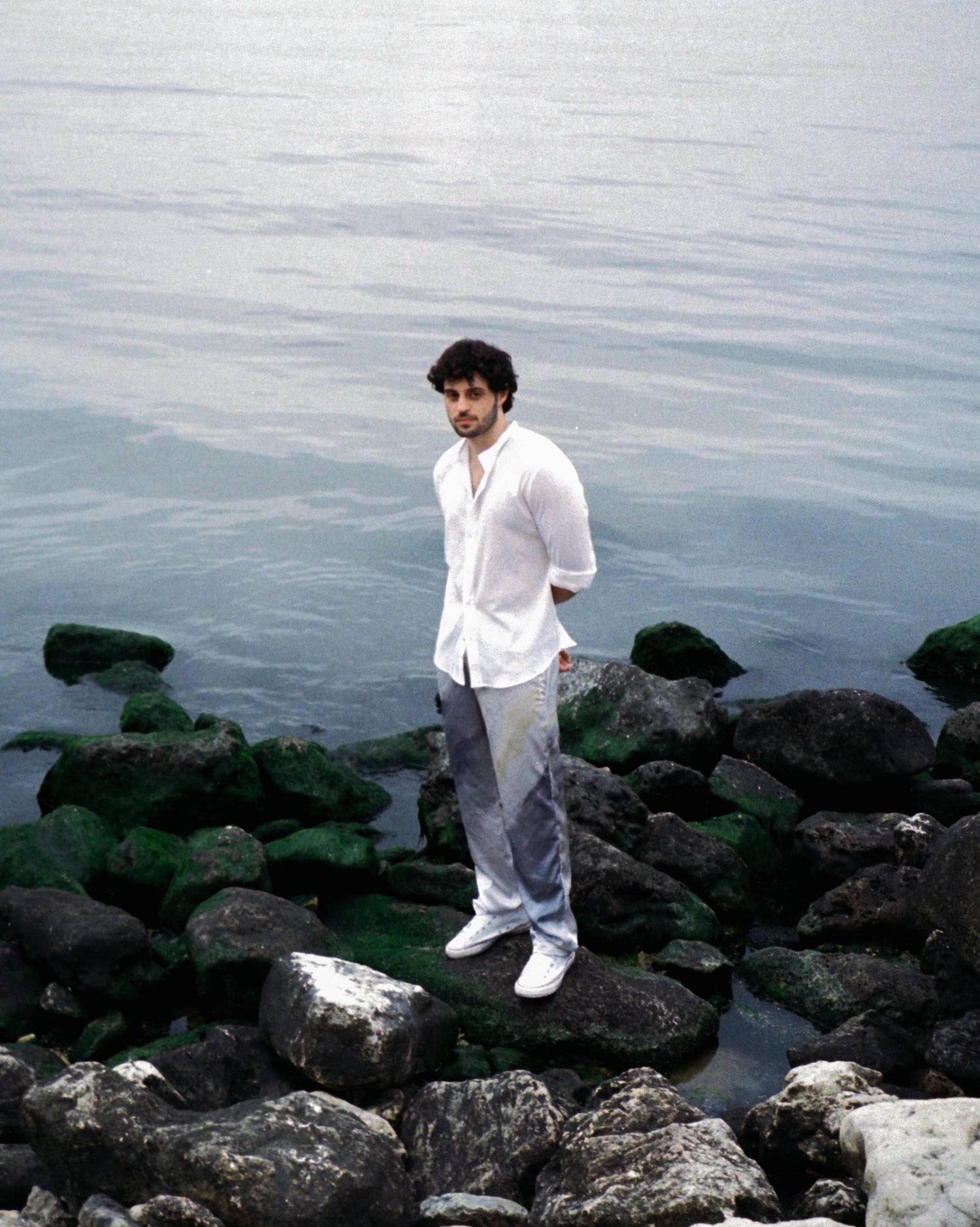 A male wearing our mercury joujete pants while standing on the rocks by the beach in Lebanon.