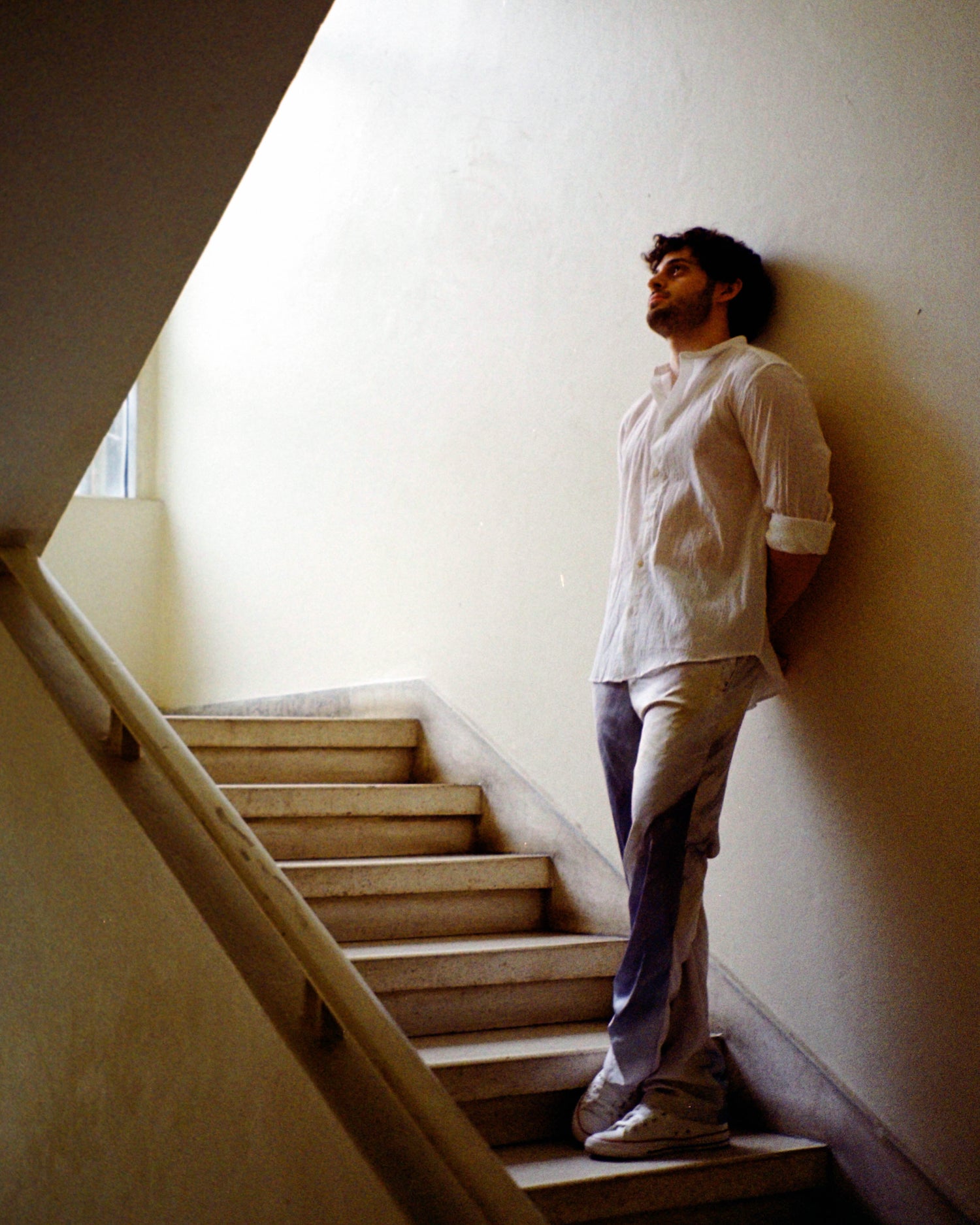 Male wearing our mercury joujete pants leaning on the wall while standing on the stairs.